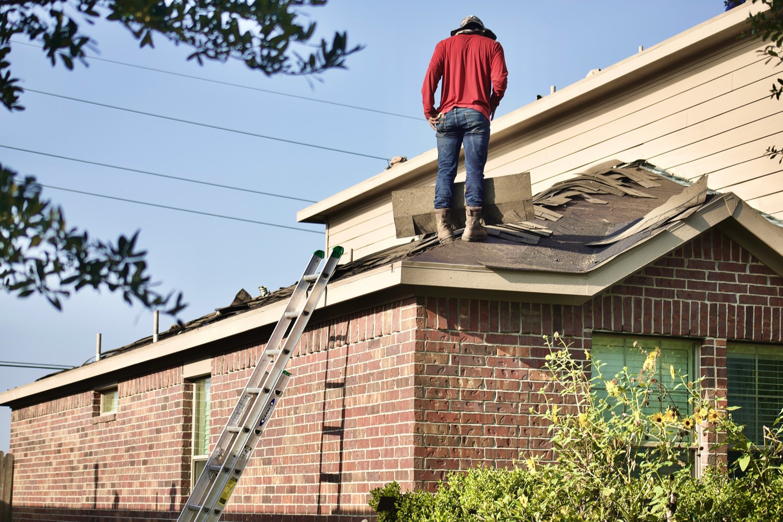 Roofer standing on a section of roof opened up for repair